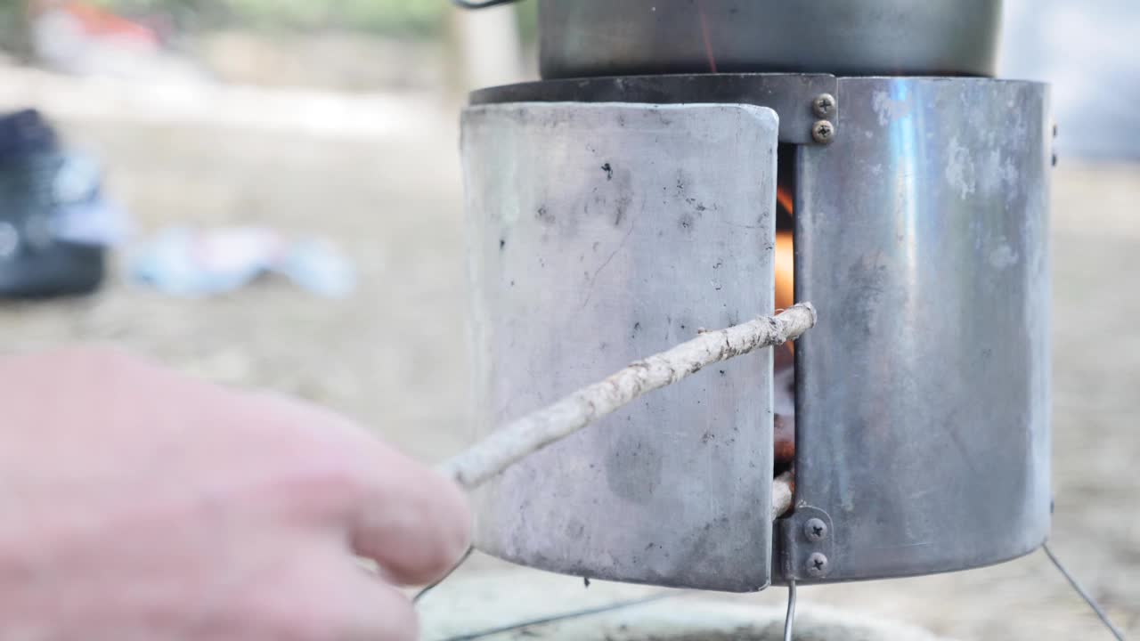 在大自然的炉子里放柴火。手把木棍放在燃烧的炉子上。烧木头的炉灶。露营旅游的概念视频素材