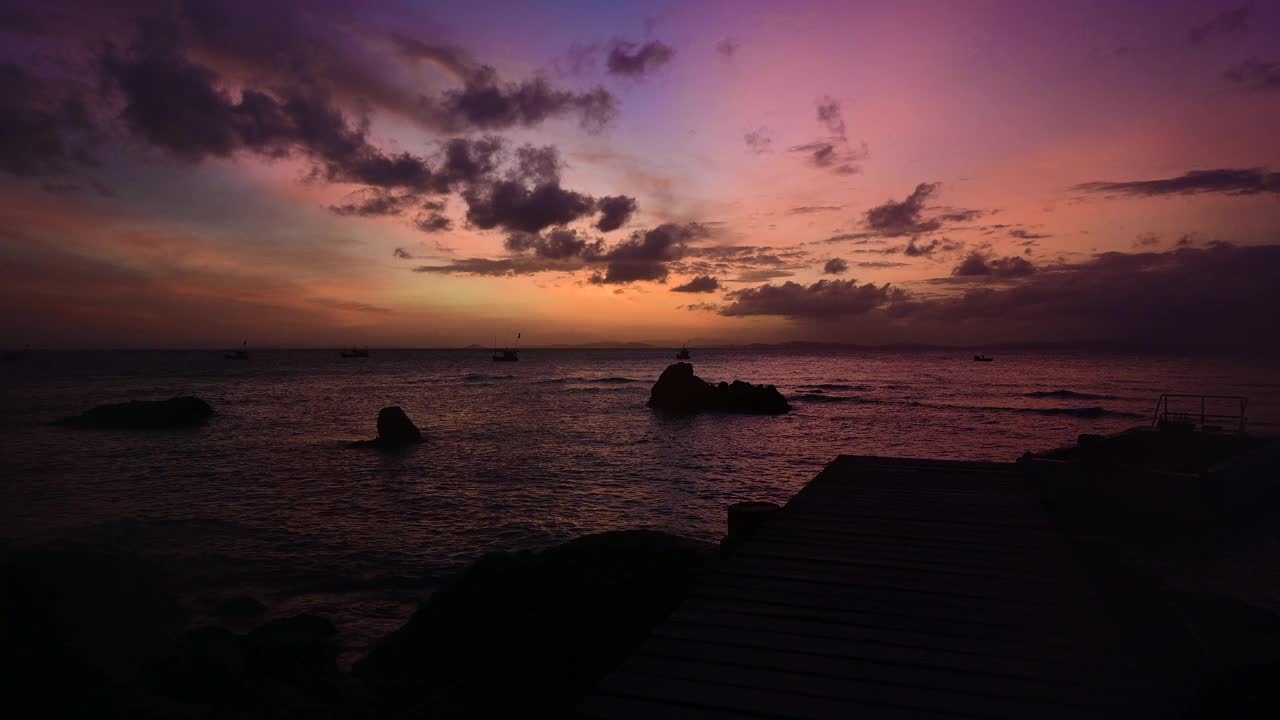 在海滩上欣赏到色彩斑斓的日落，伴随着海浪和云朵视频素材