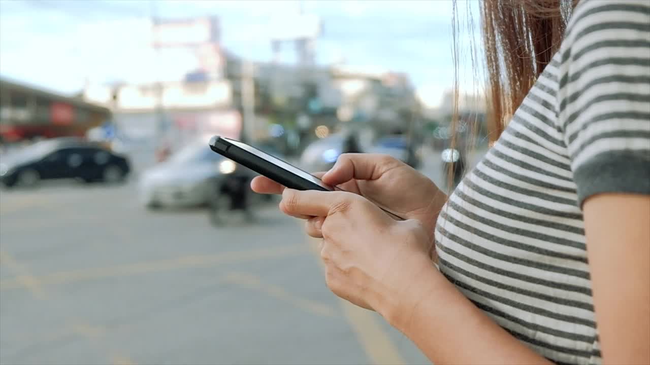 女人的手在城市购物街使用智能手机，搜索或社交网络的概念，慢动作，接近。视频素材