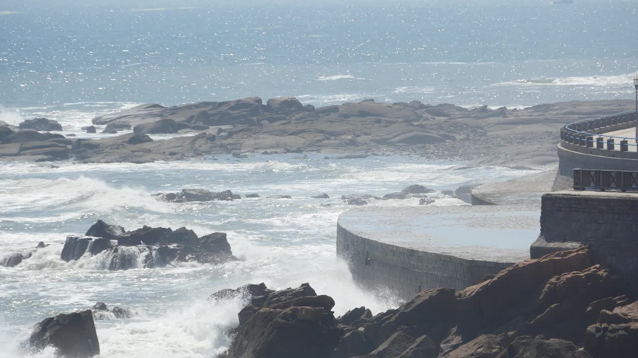 4k海浪冲过堤坝，人们上岸。海洋海水和海岸岩石浪涌海岸。视频素材