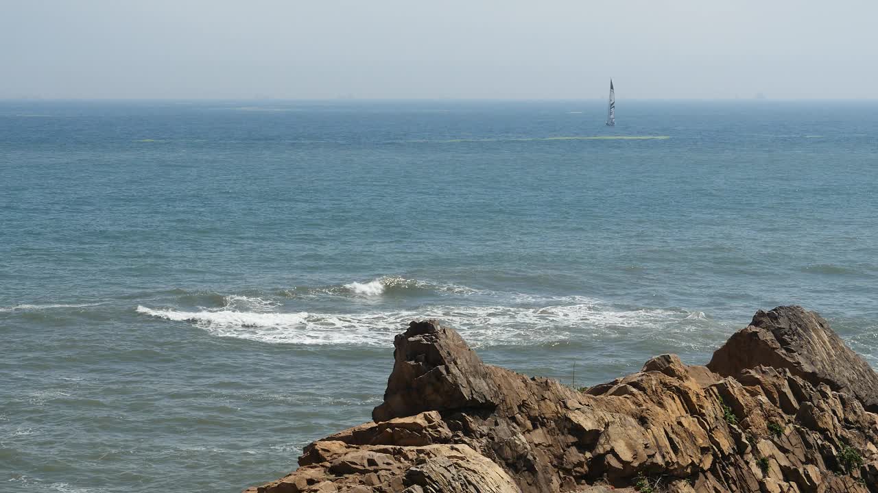 4k帆船航行在广阔的海洋，海水海浪表面和海岸岩石。视频素材