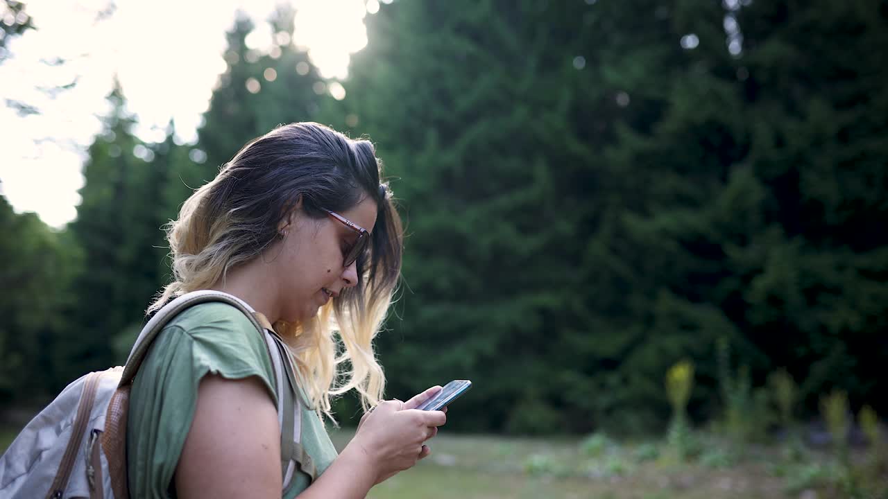 年轻女子在森林里行走时使用GPS视频素材