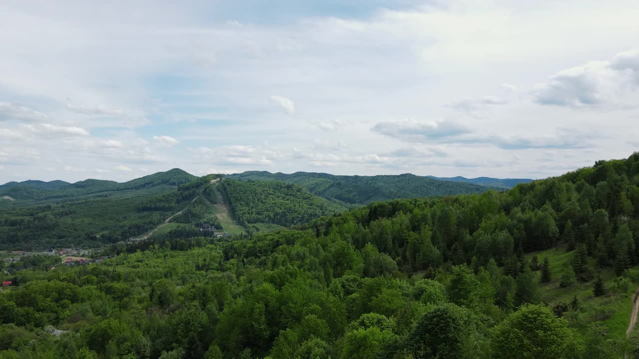 无人机拍摄飞越树梢，美丽的夏季绿色山脉在多云的天空背景。公园探险和旅游目的地的旅游和旅游欲望视频素材