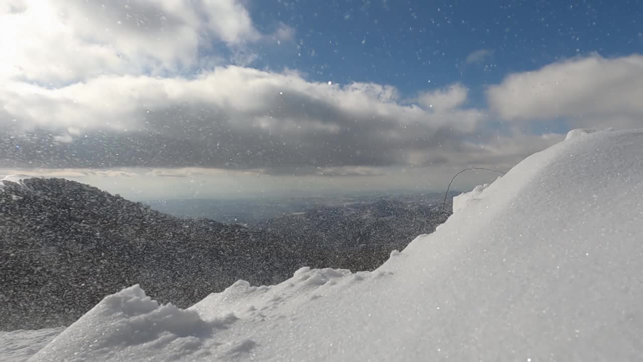 在寒冷的冬日里，暴风雪中飘起的雪花和山上的强风。慢动作视频素材