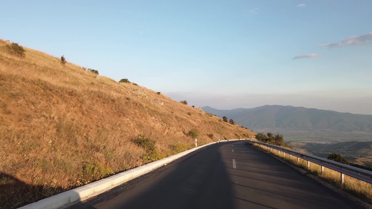 波夫在高海拔的乡村公路上行驶，穿过乡村连绵起伏的丘陵和山脉视频素材