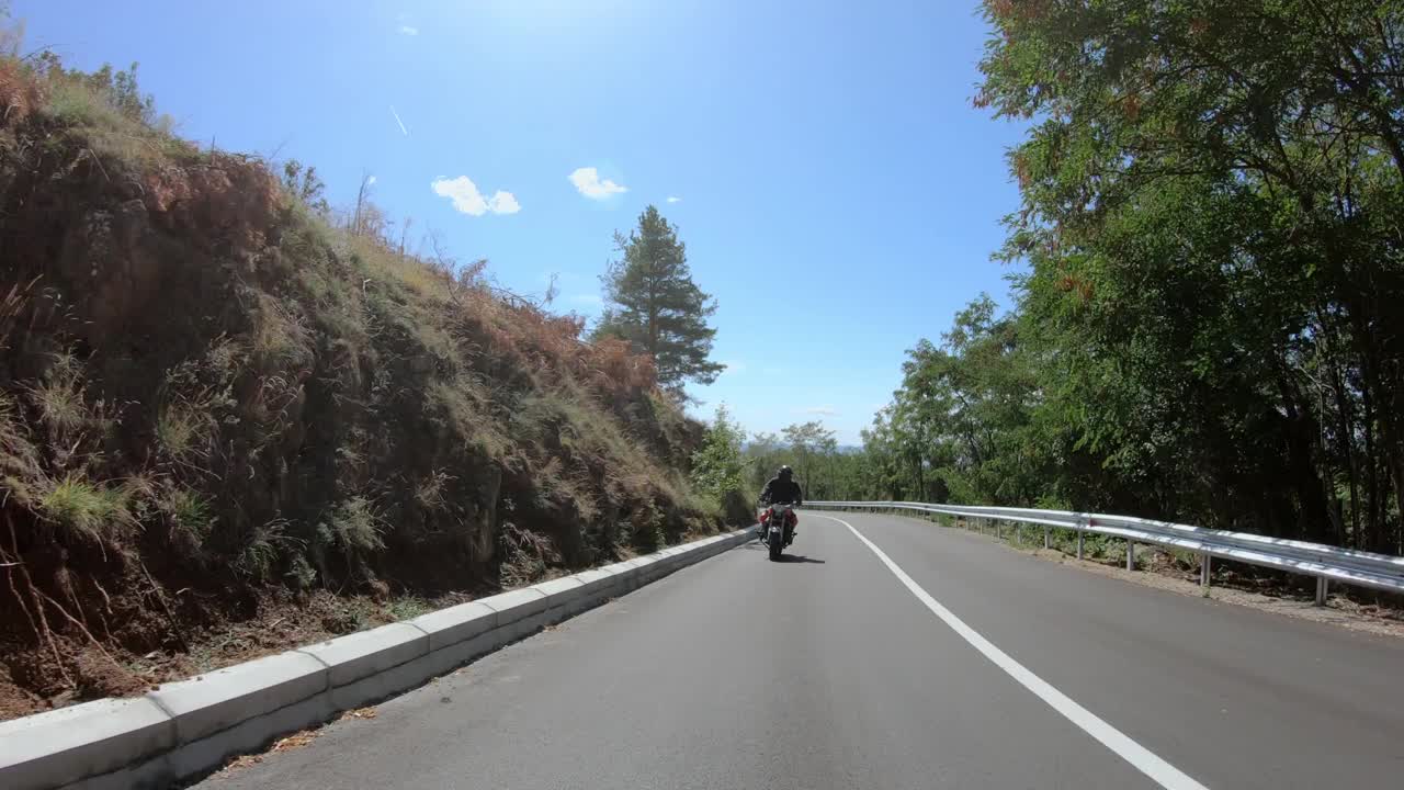 摩托车特技骑自行车在山区乡村公路和做wheelie摩托车视频素材