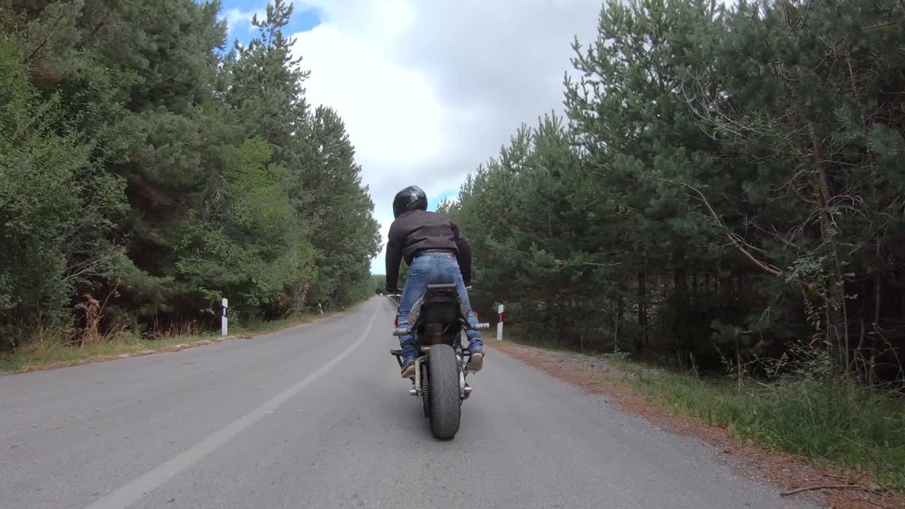 摩托车特技骑自行车在山区乡村公路和做wheelie摩托车视频素材