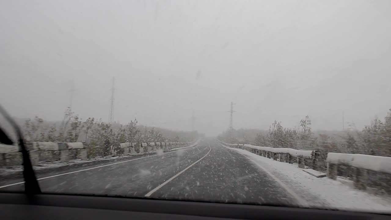 汽车在路上行驶，下着雪，能见度很差。视频素材