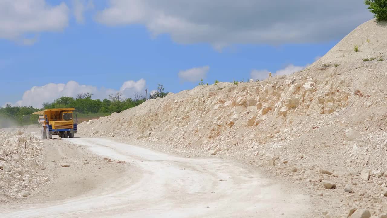 在建筑工地上工作的挖掘机。一台挖掘机和一辆卡车在挖掘和装载建筑土。一个工业区。开放地区的工业。工业水泥加工设备。视频素材