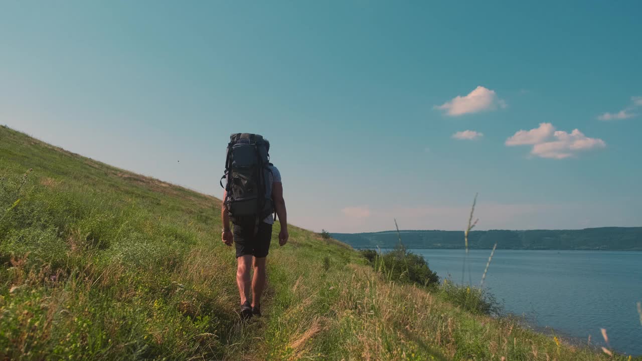 背着背包沿着美丽的海岸徒步旅行的人。慢动作视频素材