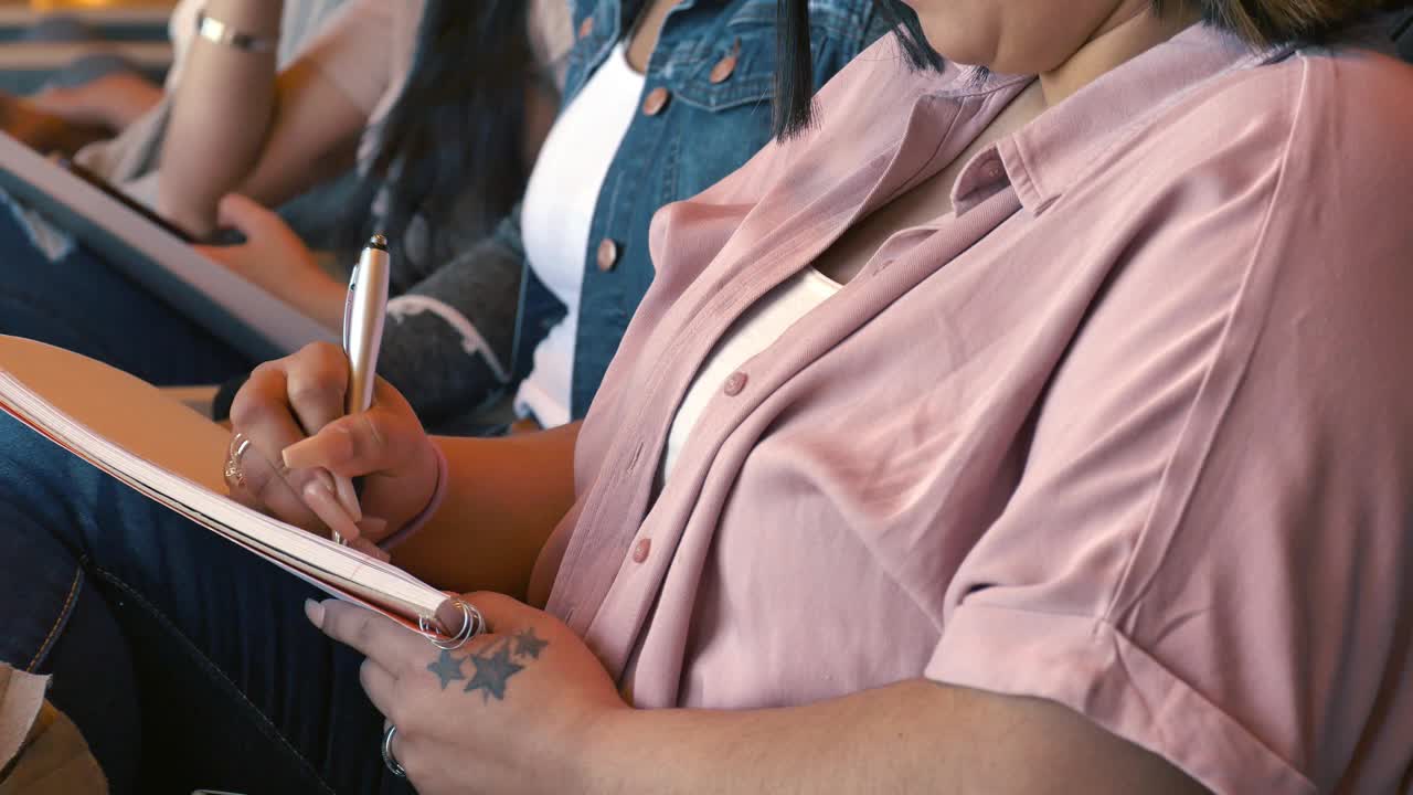 女大学生在教授讲课时记笔记视频素材