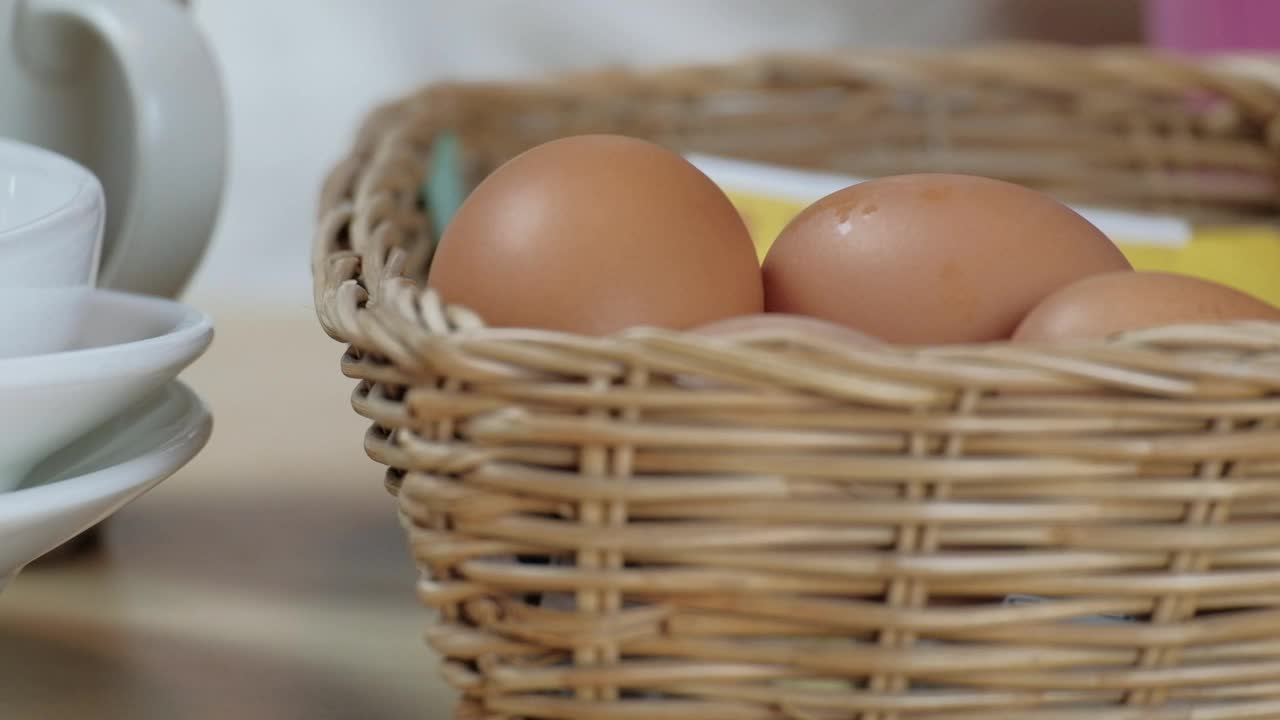 厨师在烹饪前将新鲜鸡蛋堆放在木桌上的篮子里。视频素材