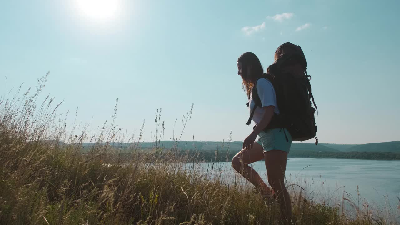 那位年轻女子背着背包沿着美丽的海岸徒步旅行。慢动作视频素材