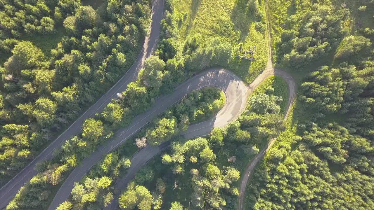 鸟瞰图的蜿蜒的道路与割草汽车和卡车在高山口，槽茂密的树林。视频素材