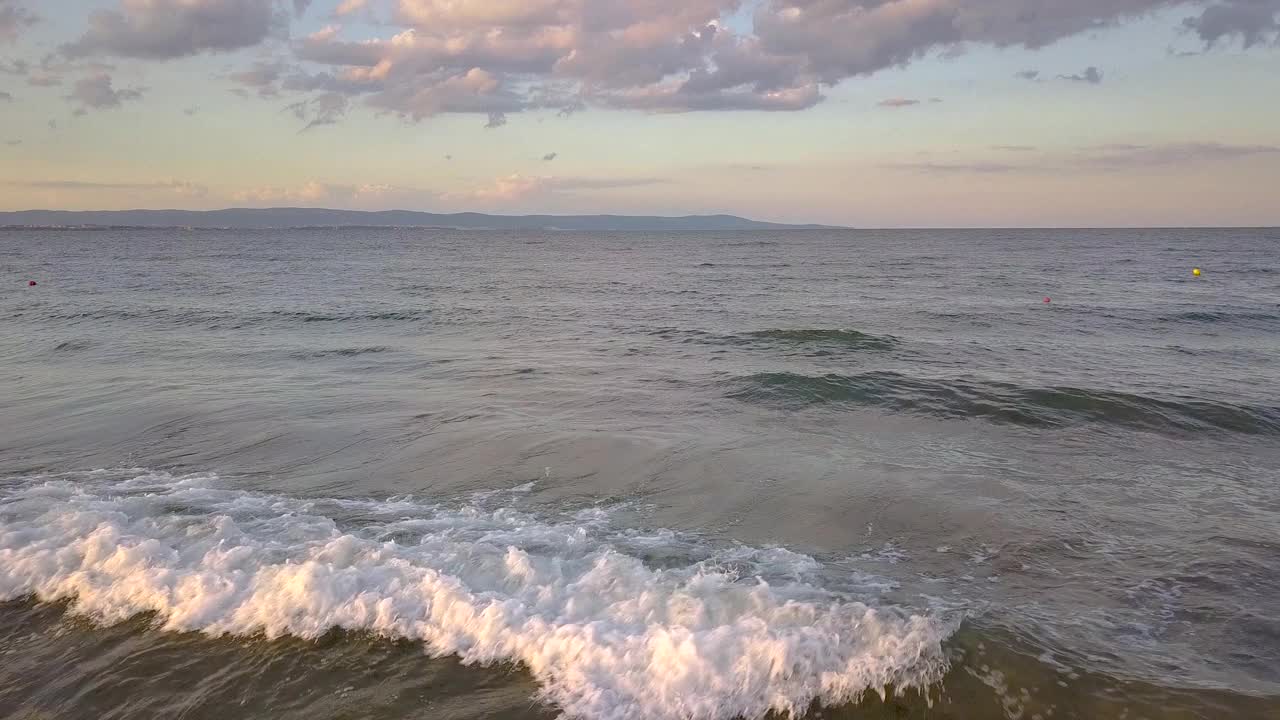 鸟瞰图的海面与蓝色的海浪在日落的天空下。视频素材