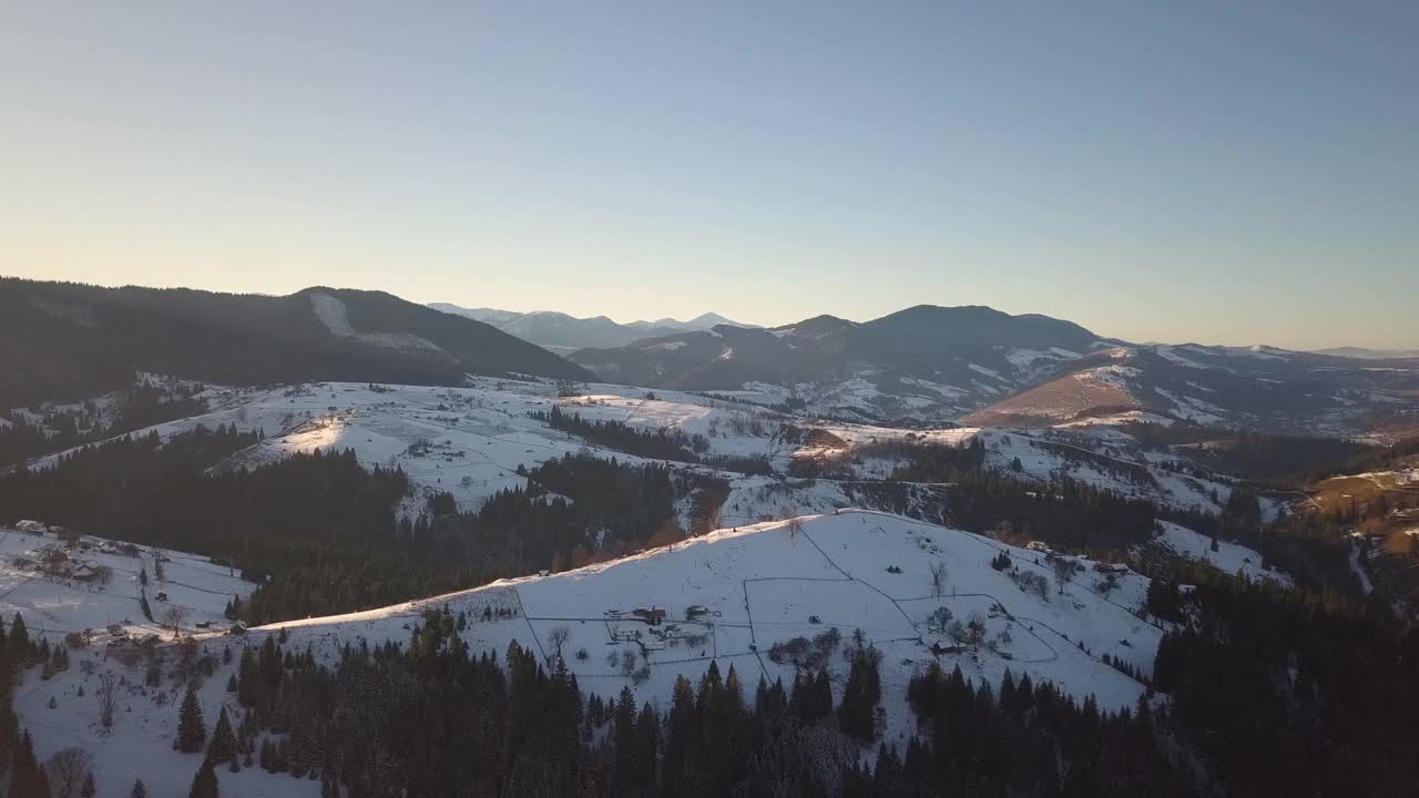 鸟瞰图小村庄与散落的房屋在冬季积雪覆盖的小山和裸露的喀尔巴阡山脉在乌克兰。视频素材