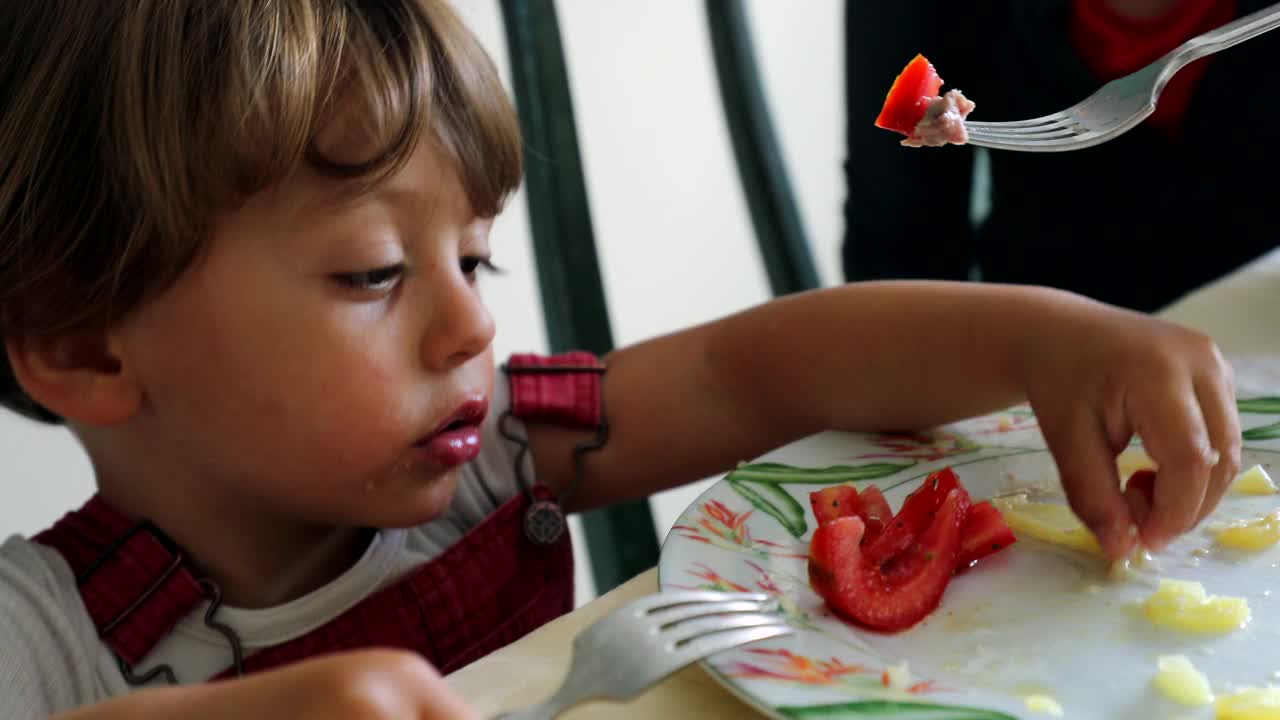 孩子用手从盘子里抓食物，母亲在给婴儿喂奶视频素材