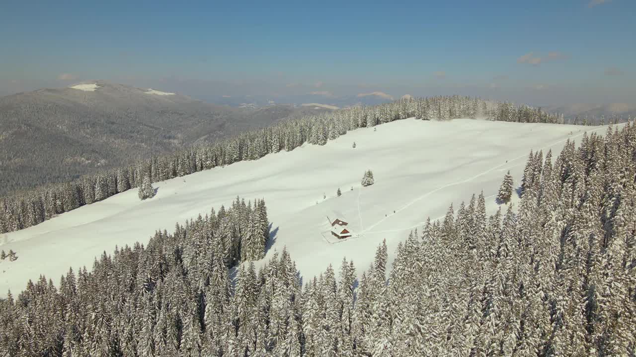 空中冬季景观与小乡村房屋之间的雪覆盖森林在寒冷的山。视频素材