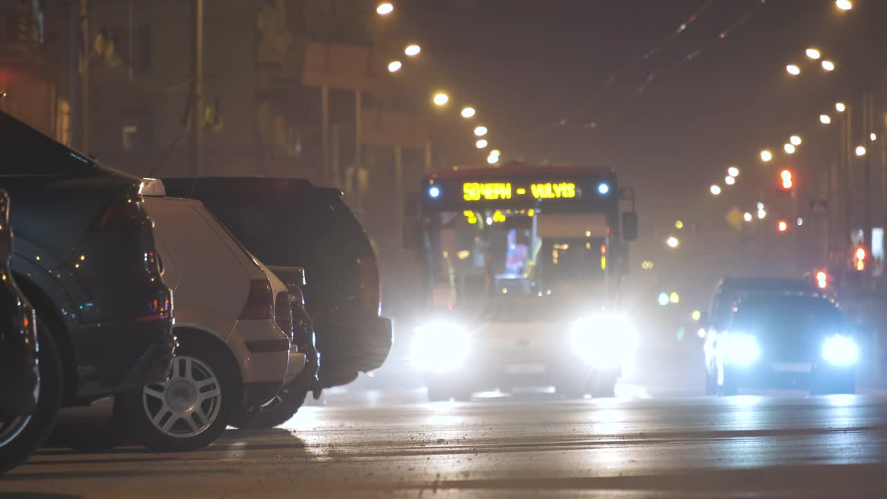 在城市街道上行驶的车辆的交通灯模糊的视野下，夜晚停在路边的汽车的特写。视频素材