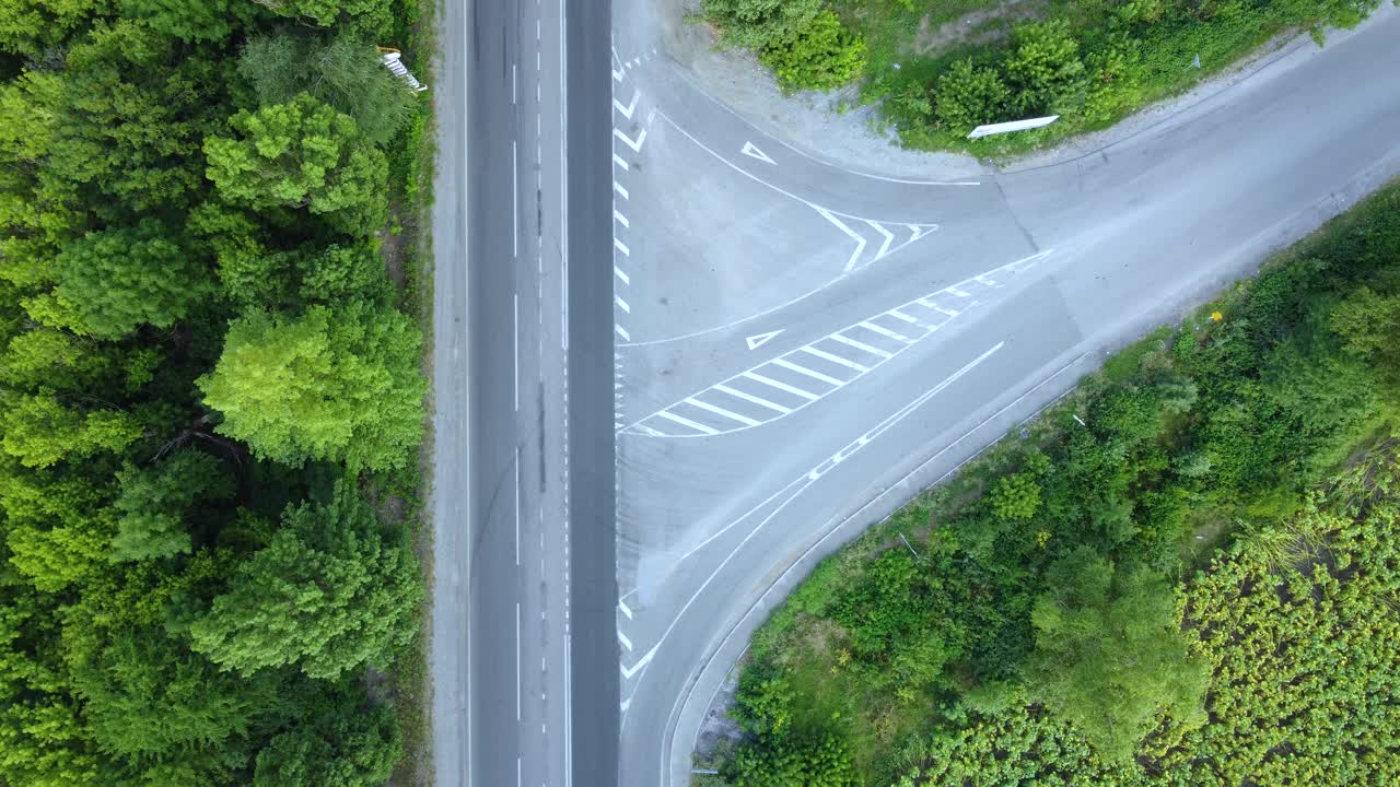 汽车在柏油路之间穿行，绿树葱茏，鸟瞰路口不相等的道路视频素材