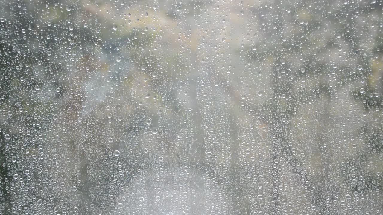 窗外下着雨，新的雨点落在玻璃上滚下来视频素材