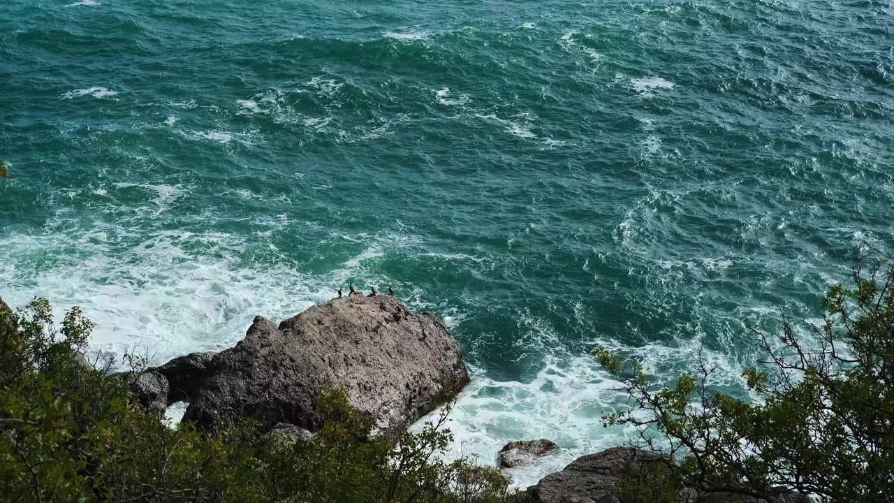 美丽的海景，蓝色的海浪拍打着海岸的岩石视频素材