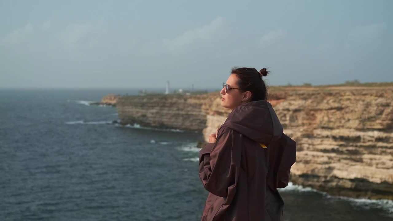 从悬崖岸线欣赏海景，女游客欣赏着地平线视频素材