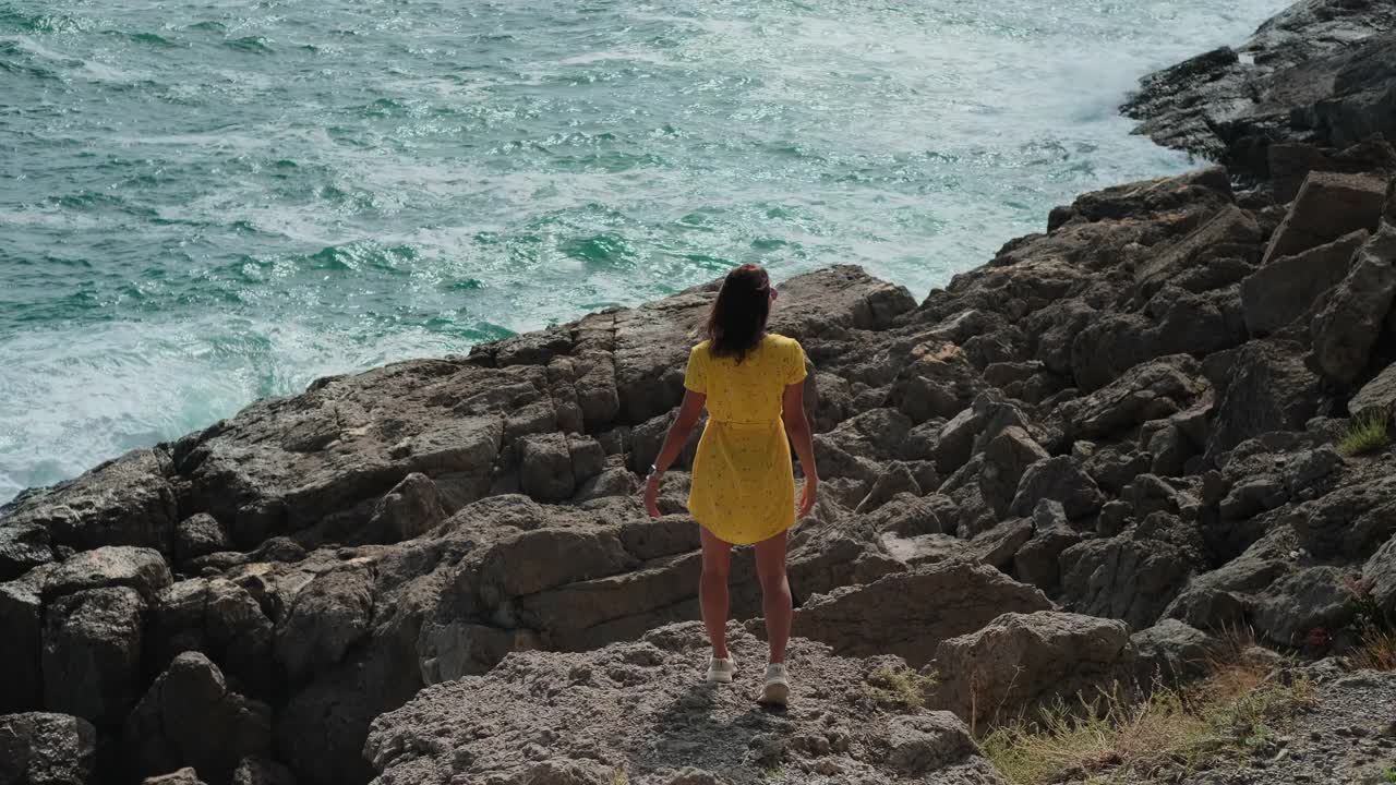 在大自然中旅行，年轻女子正在悬崖上欣赏海景视频素材