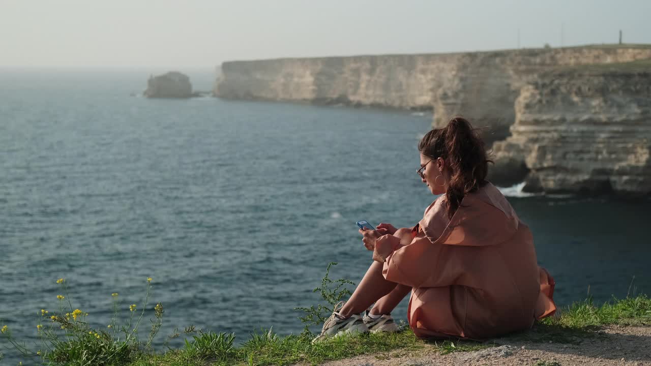 女人在海边享受孤独，用智能手机视频素材