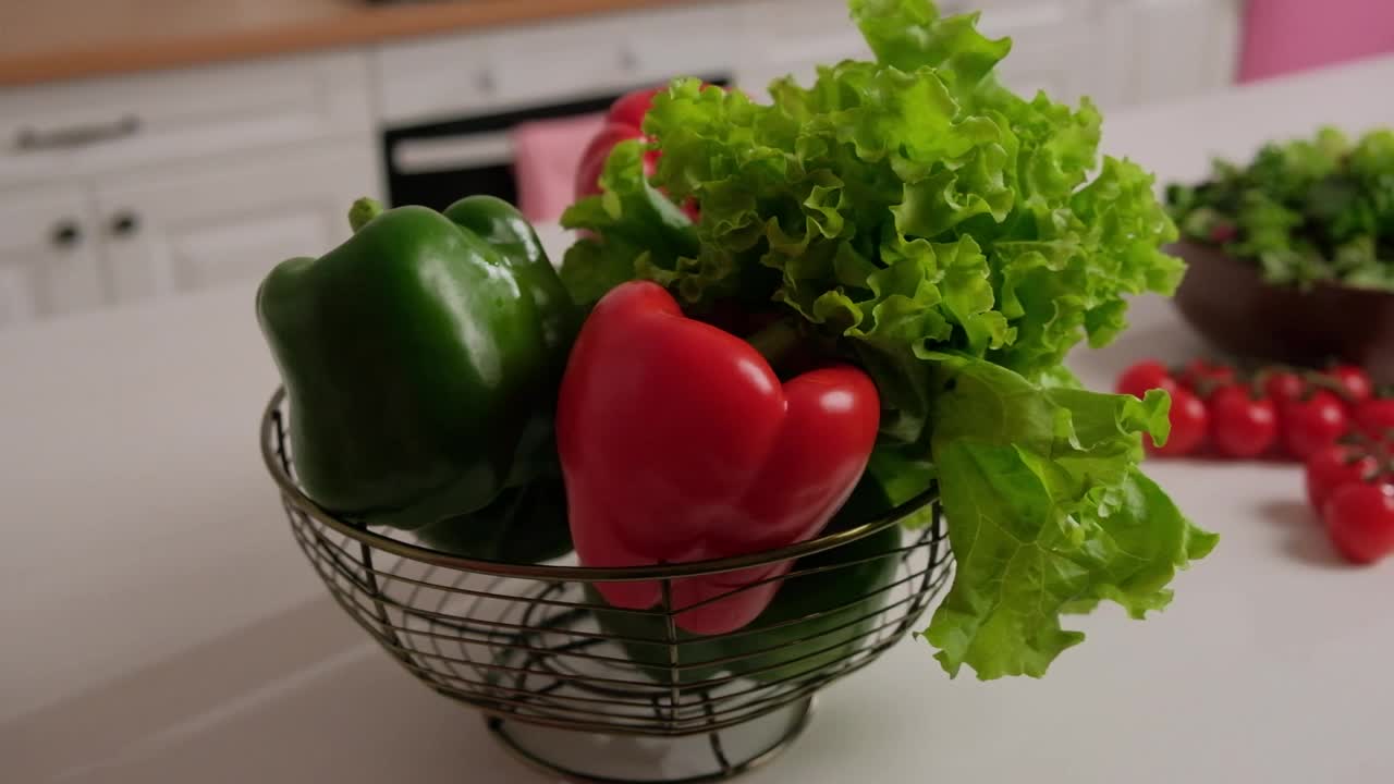 新鲜的蔬菜沙拉，红绿辣椒和圣女果放在桌子上，背景是白色的厨房视频素材