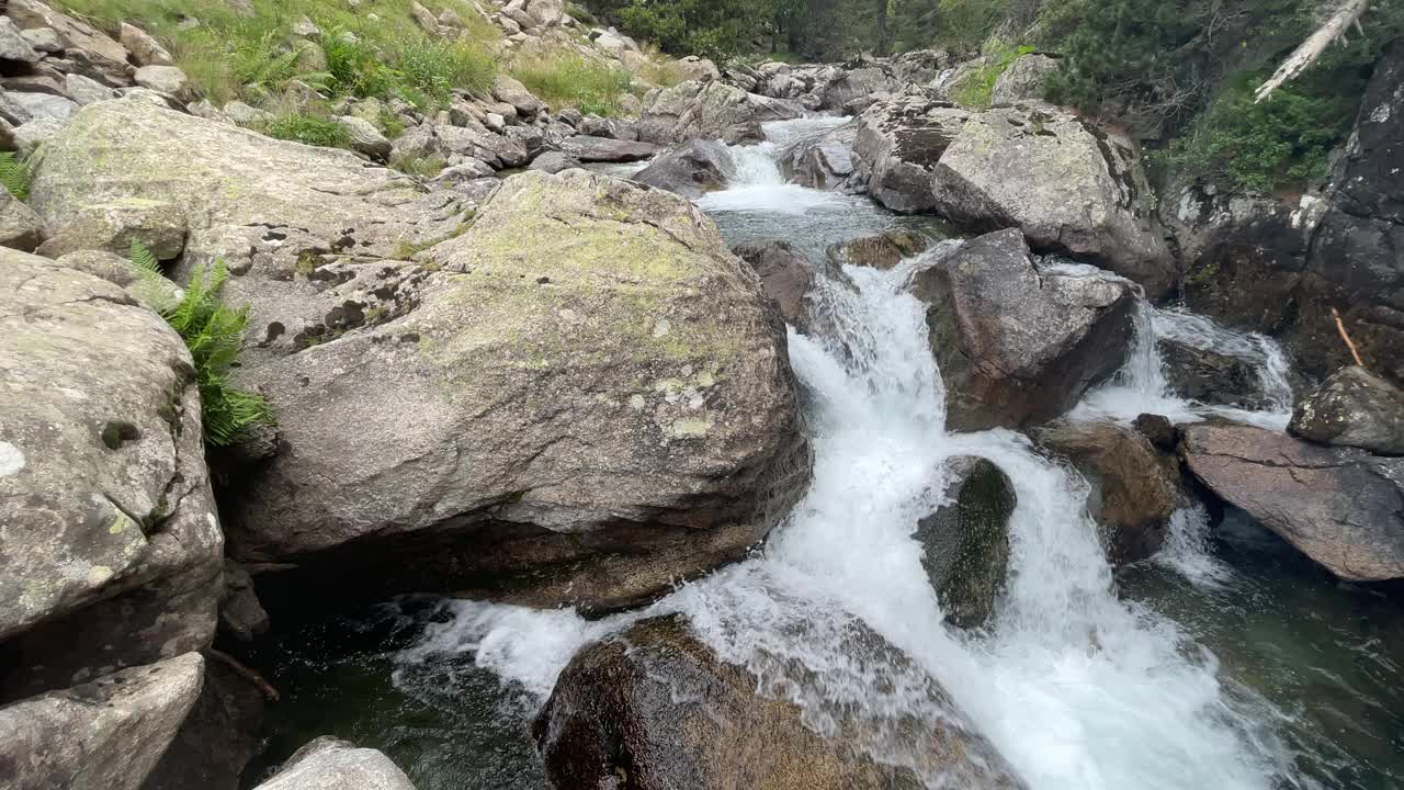 一条湍急的山河沿着它的路线在岩石之间顺流而下，以山脉为背景视频下载