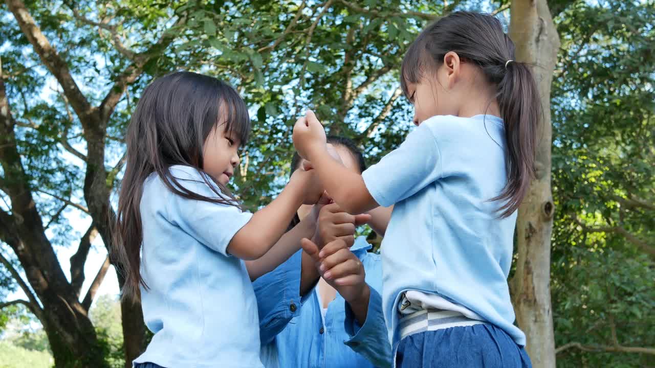 在温暖阳光的夏日，两个兄弟姐妹和妈妈在花园里欢笑和拥抱。小女孩和妈妈在公园里玩。视频素材