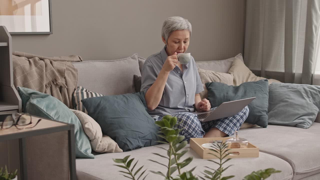 女人用笔记本电脑喝咖啡视频素材