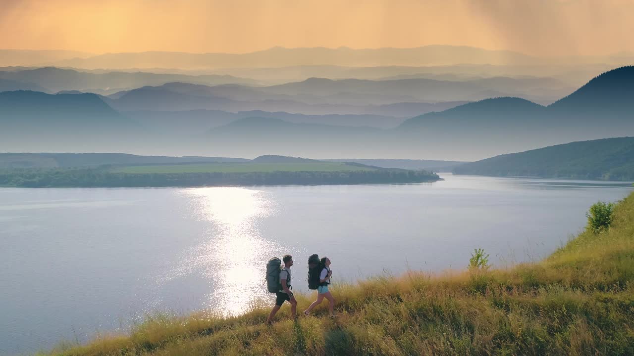 两人爬山时以风景如画的河流为背景。慢动作视频素材