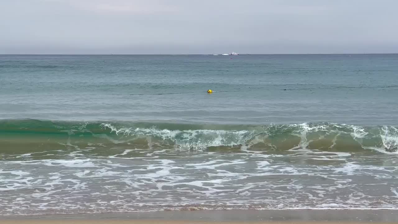 海浪在海滩上，轮船在地平线上航行视频素材