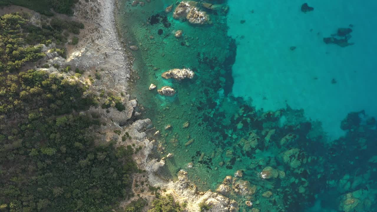 从上面看，令人惊叹的鸟瞰绿色和岩石海岸线沐浴在蓝绿色，水晶般的清澈的水。意大利撒丁岛的翡翠海岸。视频素材