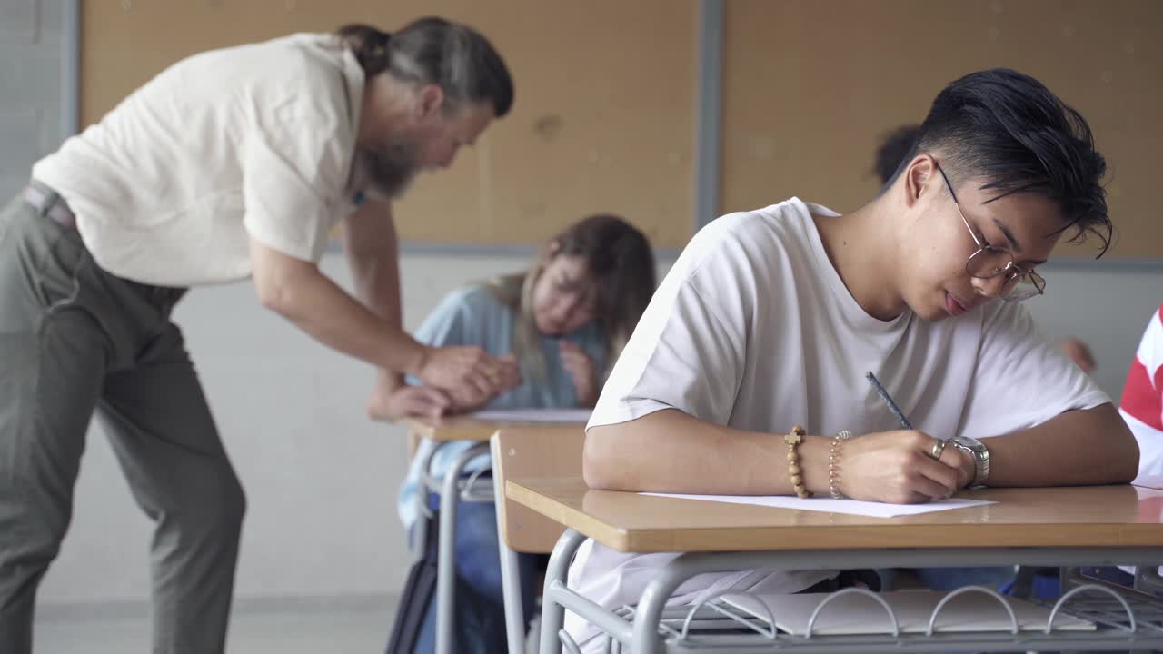 在中学教室里，亚洲学生在考试，教授在讲解习题视频素材