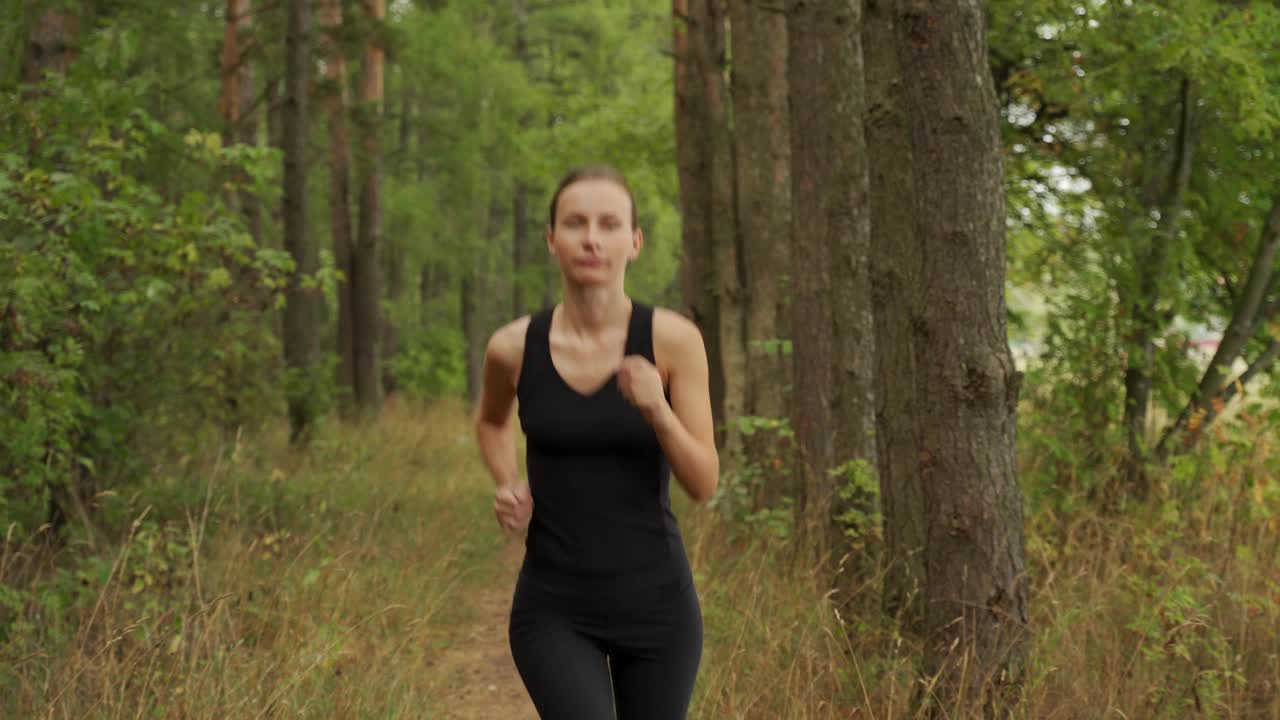 漂亮的女人在公园里跑来跑去。年轻健美的美女慢跑穿过森林视频素材