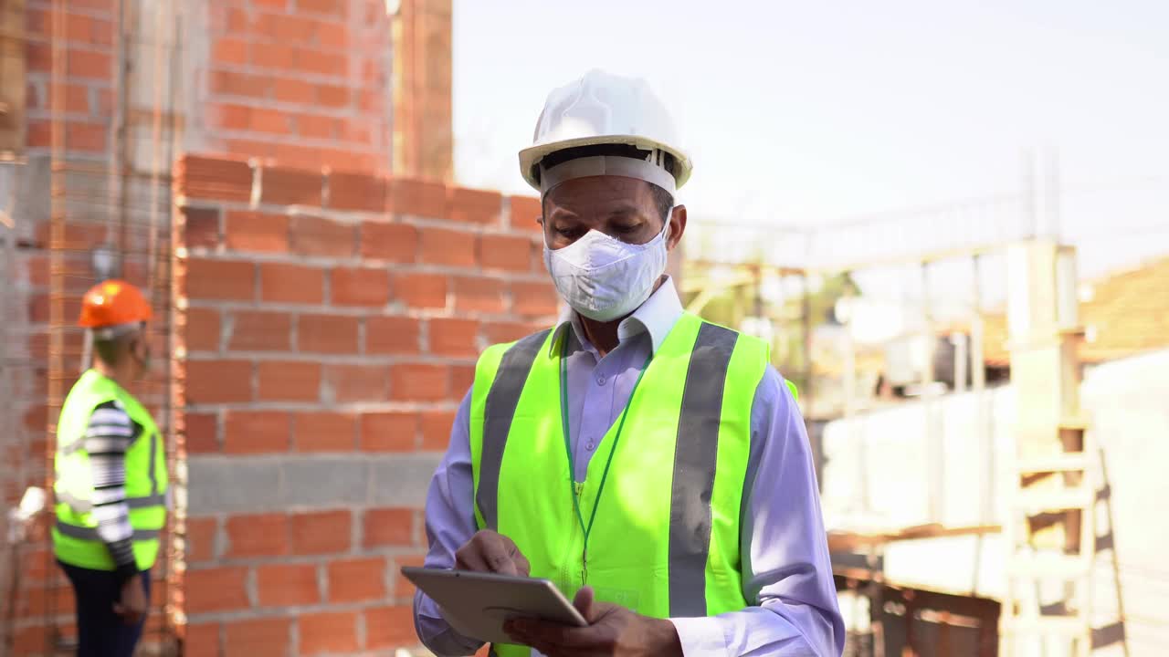 建筑工人分析在建筑工地工作的电子平板电脑上的信息视频素材