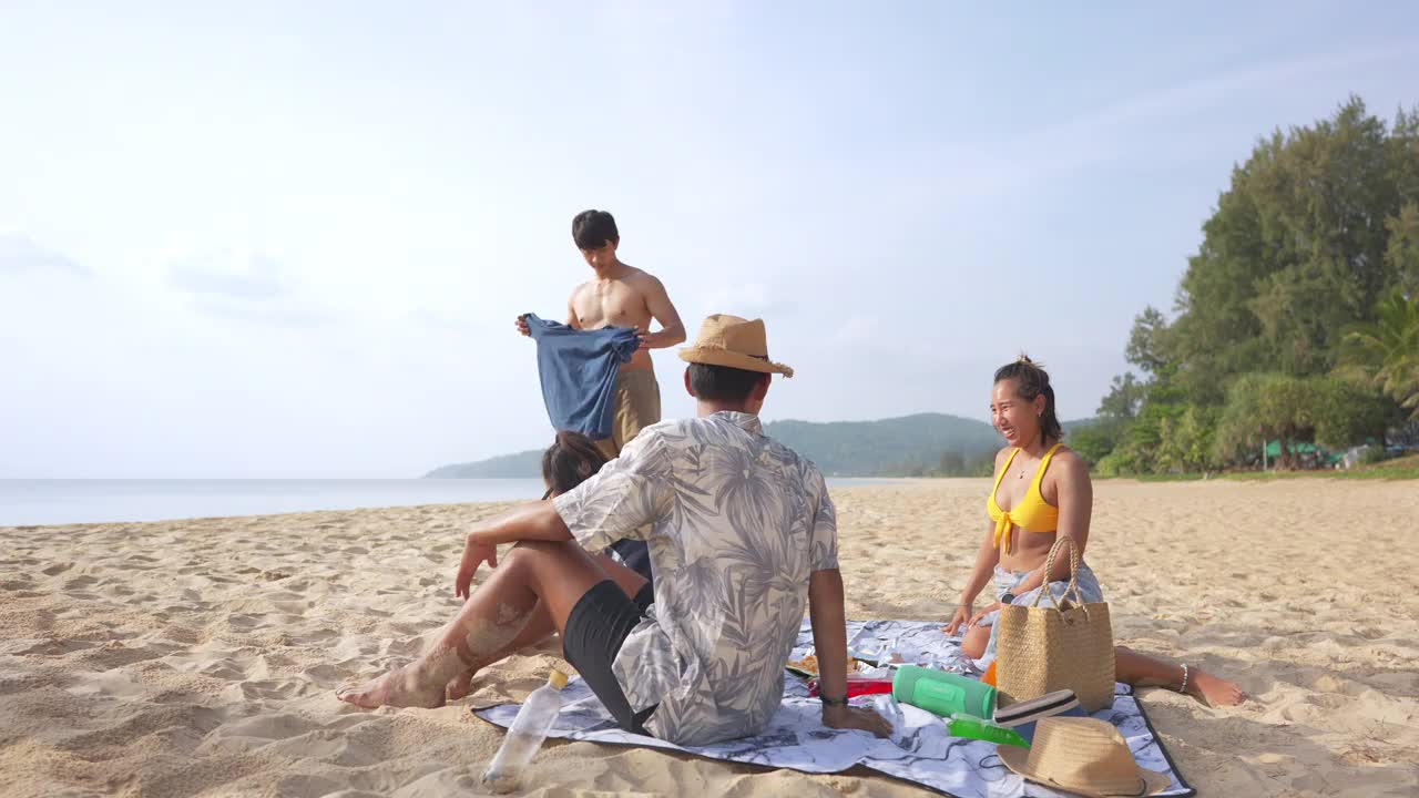 一群亚洲男人和女人朋友在夏天的假期在海滩上野餐视频素材