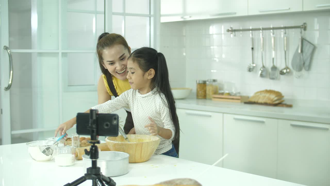 可爱的母亲和女儿在家庭厨房制作烘焙教程在线视频视频素材