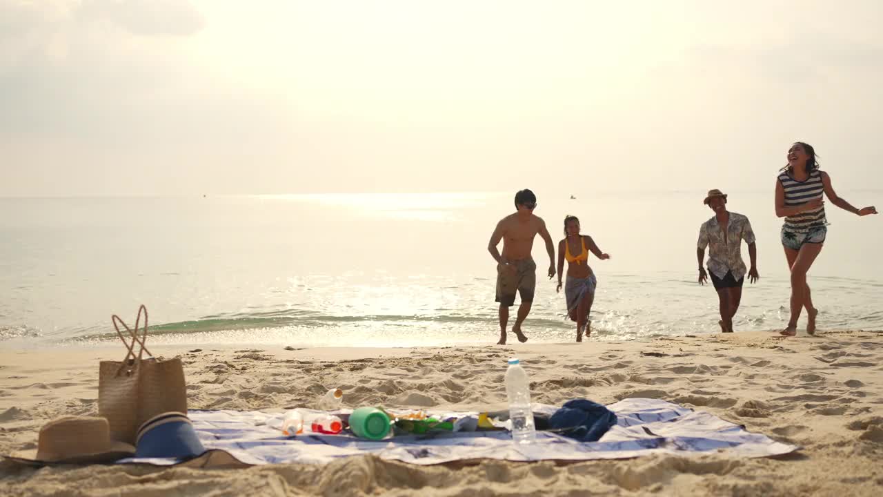 一群亚洲男人和女人朋友在夏天的假期在海滩上野餐视频素材