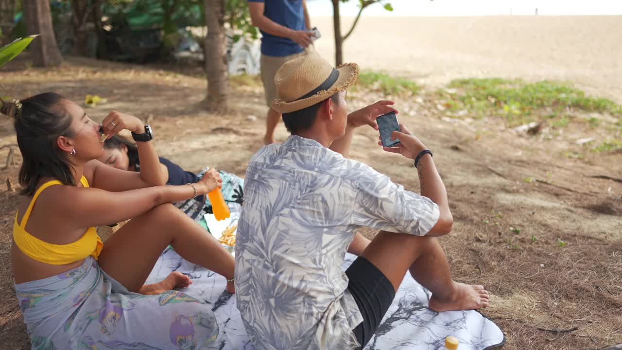 一群亚洲男人和女人朋友在夏天的假期在海滩上野餐视频素材