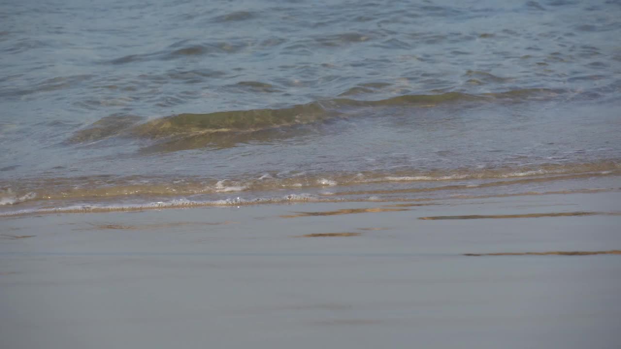 地中海的波浪在阳光下翻滚，向着沙滩。近距离拍摄平静的泡沫水。视频下载