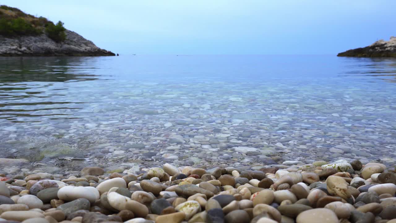 海滩上卵石的特写，背景是平静的大海。阴沉沉的夏日视频素材