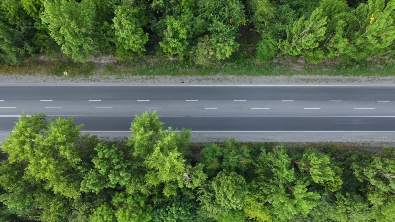 在树间的道路上方缓慢地飞行。沥青车辆的交通视频素材