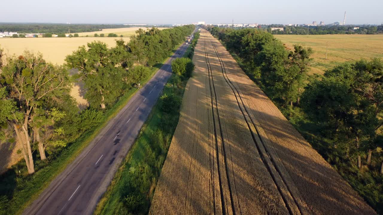 黄昏时分，无人机在高速公路、麦田和绿树上飞行视频素材