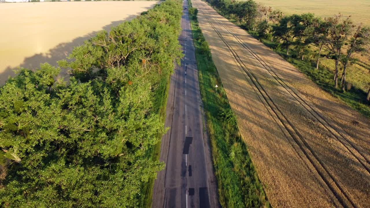 日落时分，无人机在高速公路、麦田和绿树上飞行视频素材