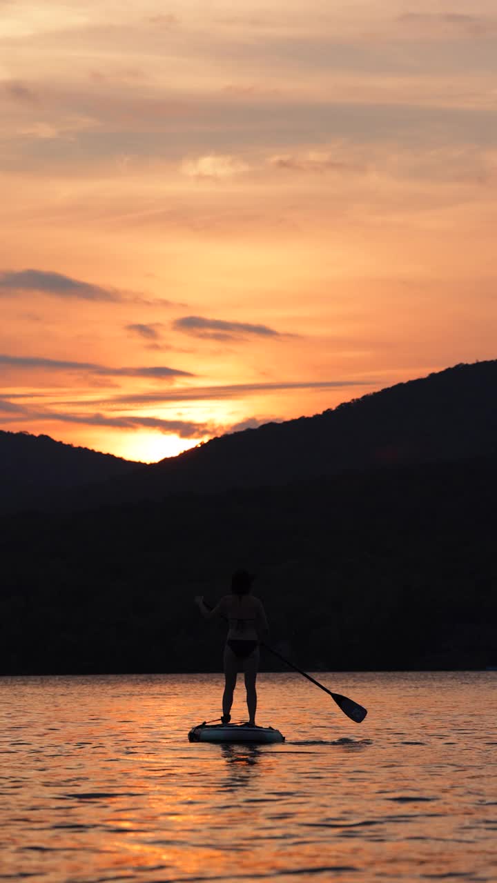 女子在夏天的日落之湖上冲浪视频素材