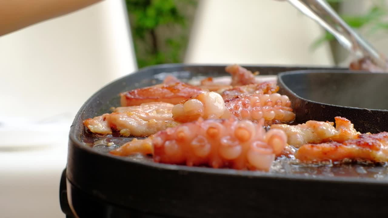 亚洲涮锅，在烟熏平底锅上烤猪肉、鱿鱼和培根。视频素材